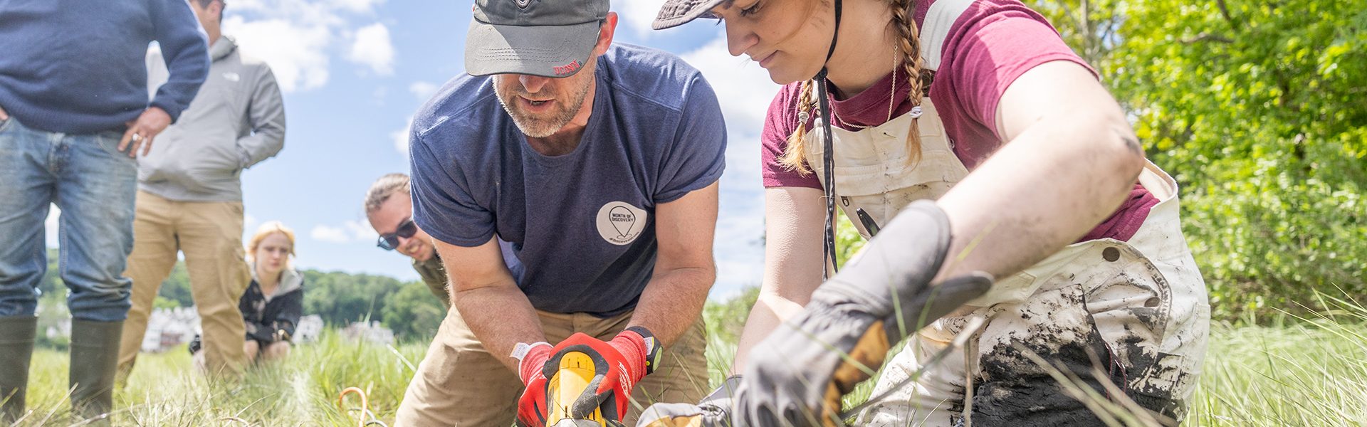 Professor William Ouimet and a student work to cut the pipe of the soil cores their team collected on Grannis Island.